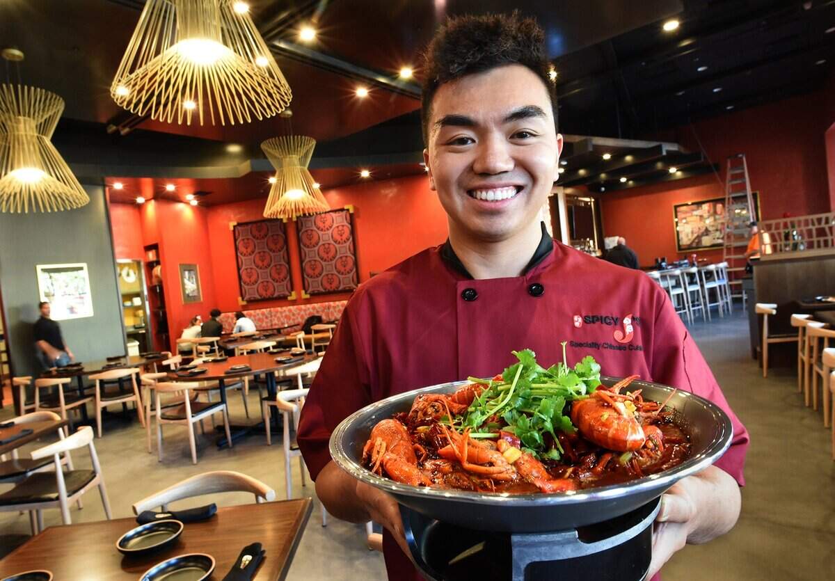Jason Lin holds a platter of hot and spicy crawfish at his new Spicy J’s Specialty Chinese Cuisine in River Park in this file photo from 2019.