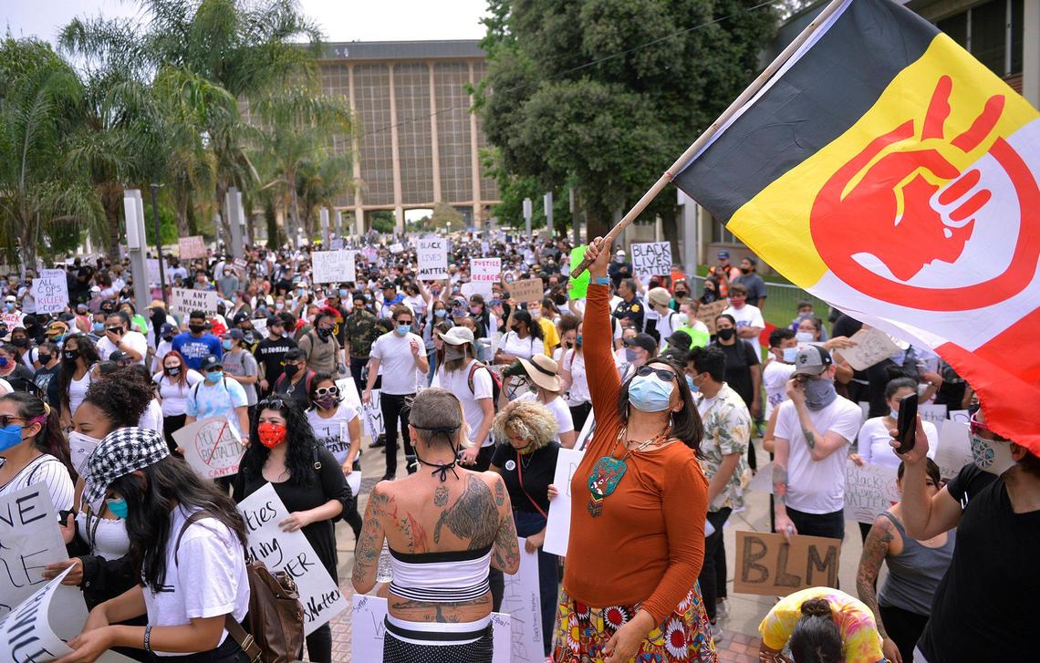 Josephine Fuentez, right, holds up an American Indian Movement flag as a crowd gathers Sunday, May 31, 2020, on the Mariposa Mall in front of the Fresno Police Department during a protest of the George Floyd death.