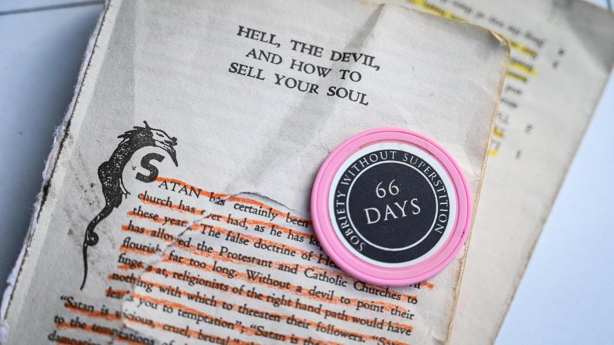 Stephanie Hahn’s book on Satanism, with her sobriety chip after she recently found sobriety through the Satanic Temple’s Sober Faction. Photo taken at Woodward Park in Fresno on Friday, Jan. 28, 2022.