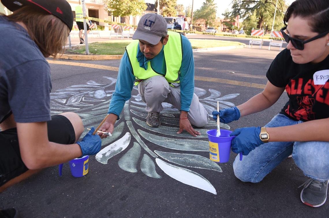 Artist Mauro Carrera, center, helps volunteers paint the intersection at N. Van Ness Blvd and Weldon Ave. Saturday, July 6, 2019 in Fresno.