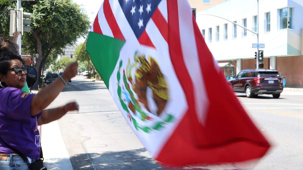 A woman waves a combination of the U.S. and Mexican flags at a noon rally in front of the federal courthouse in downtown Fresno to protest the immigration raids in Los Angeles.