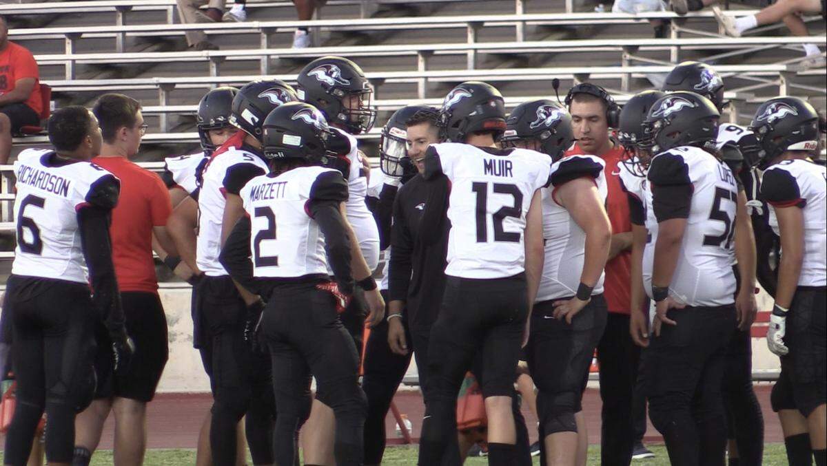 Hanford High coach Cannon Sanchez, middle, goes over plays to his team at Ratcliffe Stadium on Friday, Aug. 19, 2022.