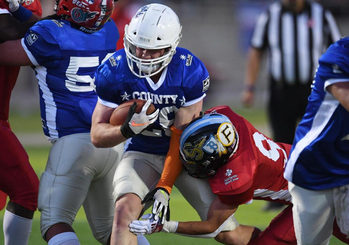 Buchanan’s Caden Rogers, left, runs past Bullard’s Brian Garcia, right, at the City/County All-Star football game held at McLane High’s stadium Friday night, June 17, 2022 in Fresno. The game ended 21-21.