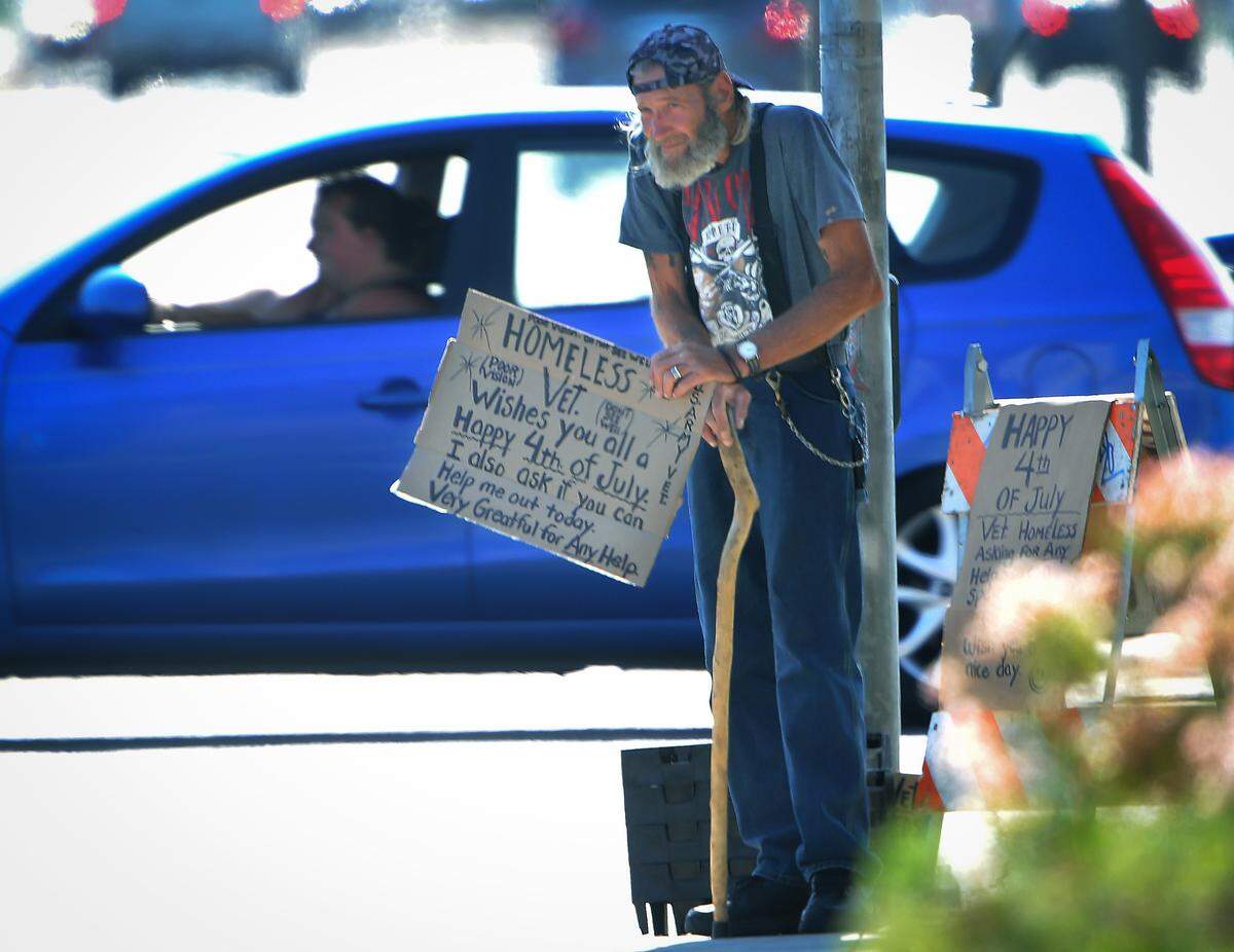 A panhandler works the corner of Fresno and Shaw, Wednesday morning, July 4, 2018.