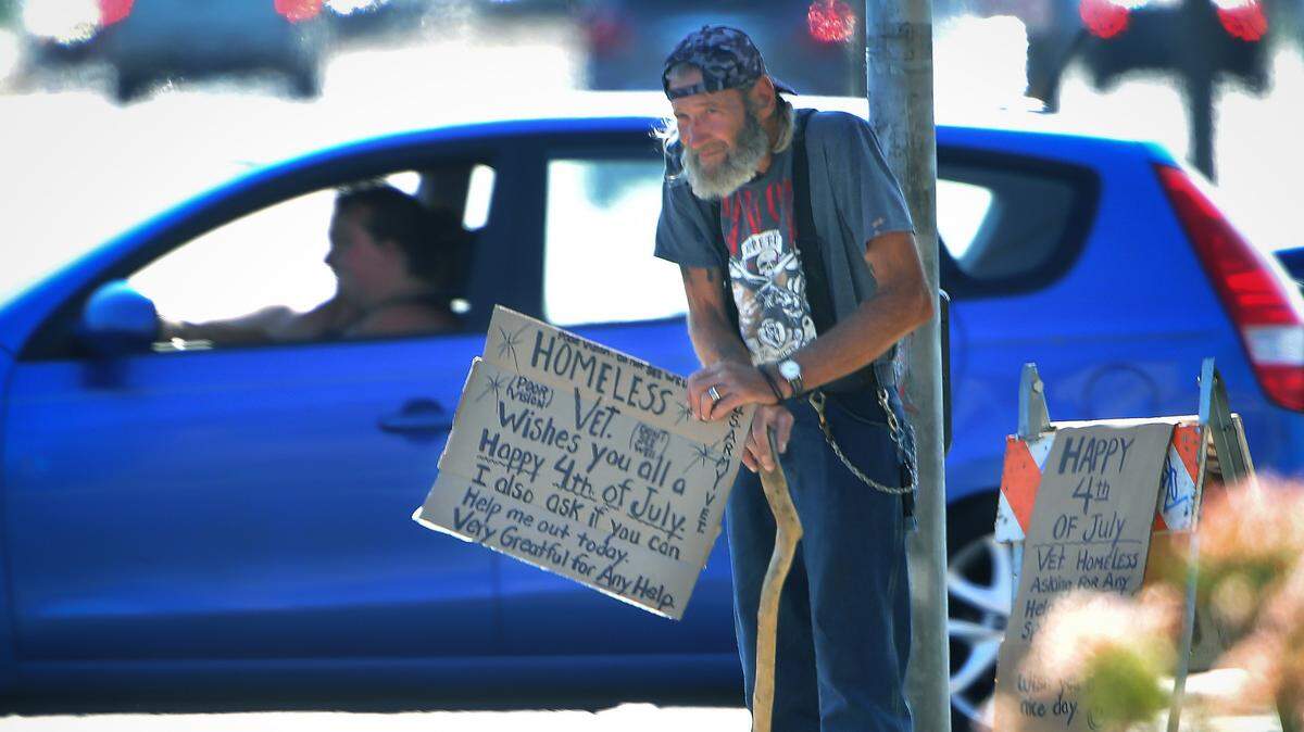 A panhandler works the corner of Fresno and Shaw, Wednesday morning, July 4, 2018.
