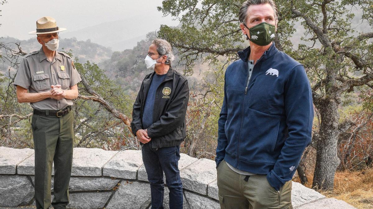 California Governor Gavin Newsom, right, listens as Sequoia-Kings Canyon National Parks Superintendent Clayton Jordan, left, discusses activity on the KNP Complex Fire while visiting Sequoia National Park with Assemblyman Richard Bloom, center, to tour the fire area and to sign a $15 billion climate change package on Thursday, Sept. 23, 2021.