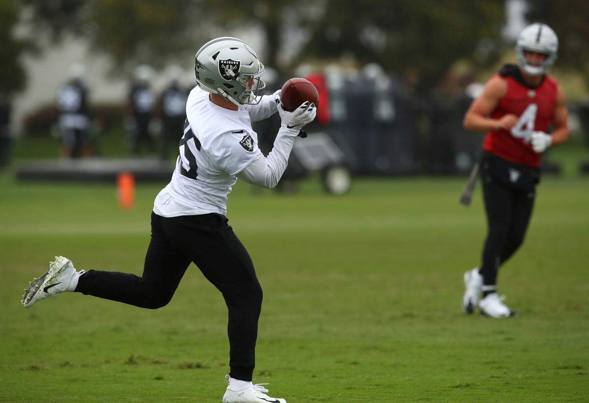 Oakland Raiders' Ryan Switzer, left, makes a catch on a pass from Derek Carr (4) during NFL football practice on Tuesday, May 22, 2018, at the team's training facility in Alameda, Calif.