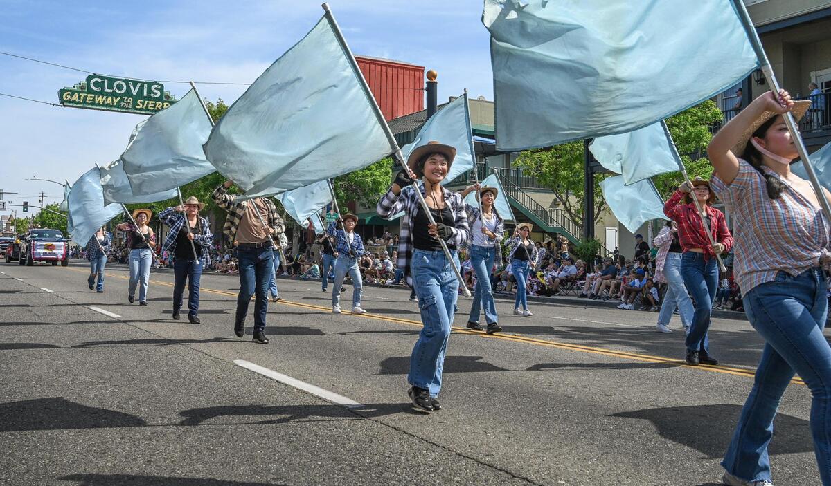 Members of the Clovis North High School marching band color guard wave their flags while marching down Clovis Avenue during the 109th annual Clovis Rodeo Parade on Saturday, April 29, 2023.