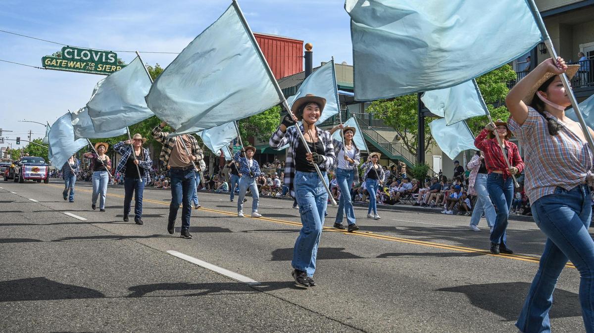 Members of the Clovis North High School marching band color guard wave their flags while marching down Clovis Avenue during the 109th annual Clovis Rodeo Parade on Saturday, April 29, 2023.