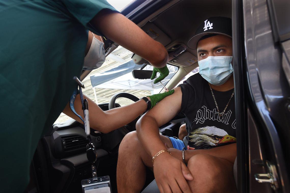 Antonio Diaz gets his second Covid-19 Pfizer vaccine from UCSF medical clerk Alex Chavez, Friday May 7, 2021, at the UCSF Covid Equity Project drive-up clinic at Fresno City College.