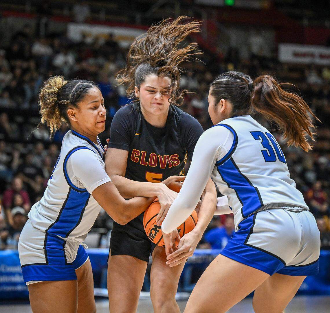 Clovis players Jada Walton, left, and Yazmin Aguilera try to strip the ball away from Clovis West's Ryleigh Schoonover during their Central Section Division 1 girls basketball championship game at Selland Arena on Saturday, Feb. 28, 2026. 