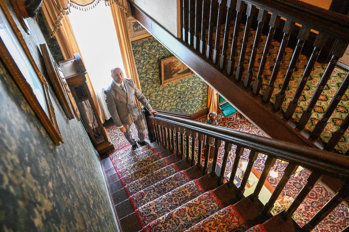 Meux Home Museum president and curator Quintin Hoskins stands at the base of the stairs that lead to the second floor bedrooms of the Meux home on Friday, April 26, 2024.