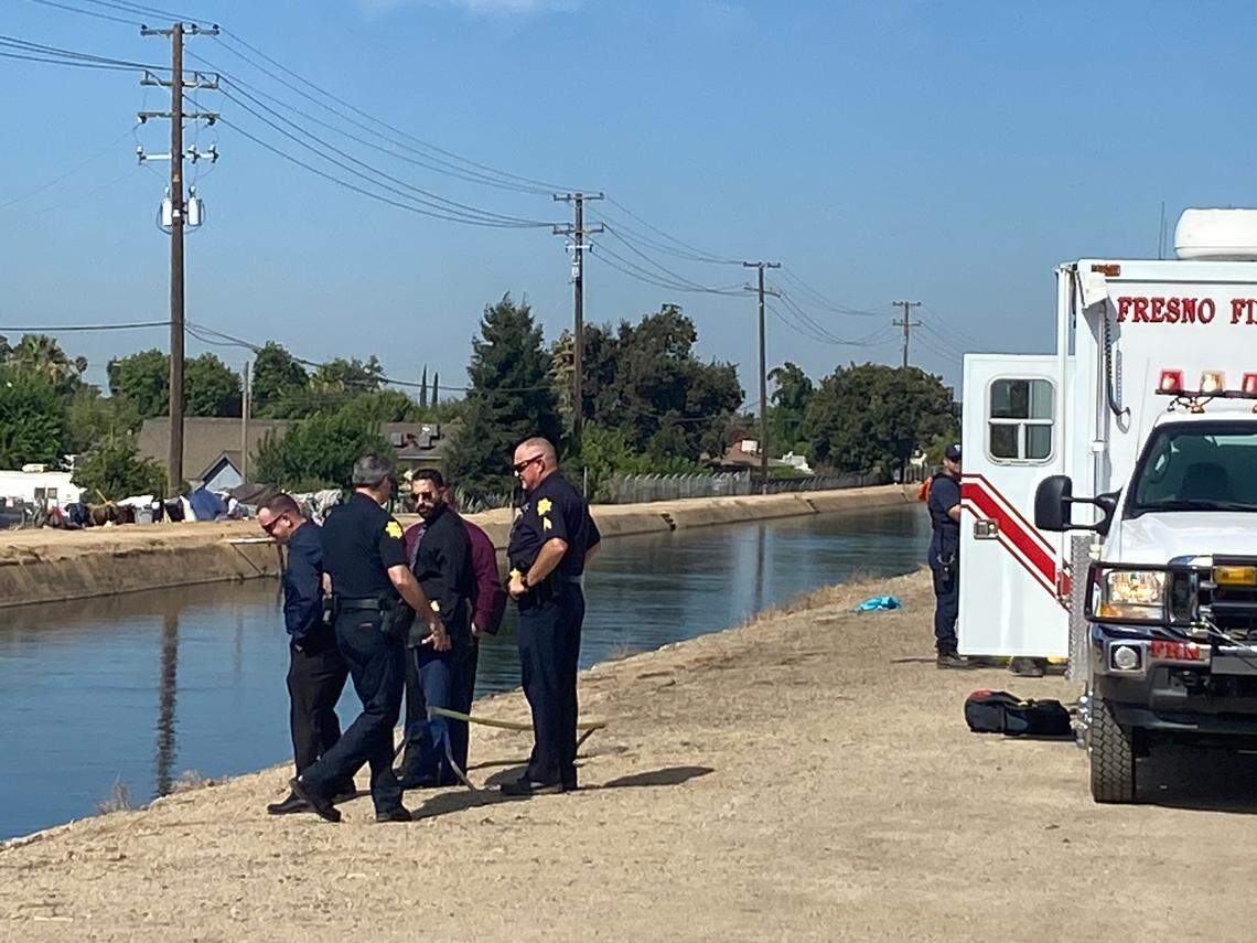 Police stand near the Fresno canal on Mckinley near Millbrook avenues on Wednesday, Aug. 16, 2023, where a body was pulled from the water before 10 a.m., according to police.