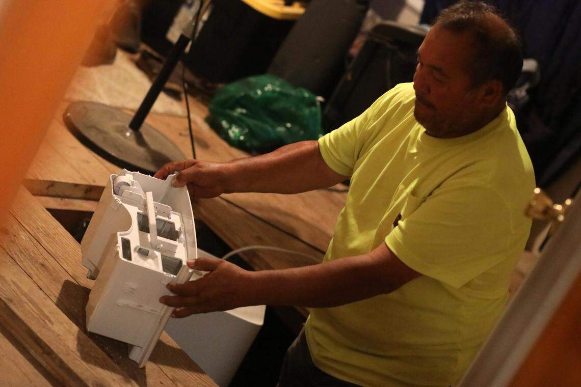Woodlake resident Gabriel Vasquez on July 20, 2023, examines the dehumidifier that is drying out flood water in his home’s foundation. He is one of many Tulare County residents whose house flooded during the winter storms.