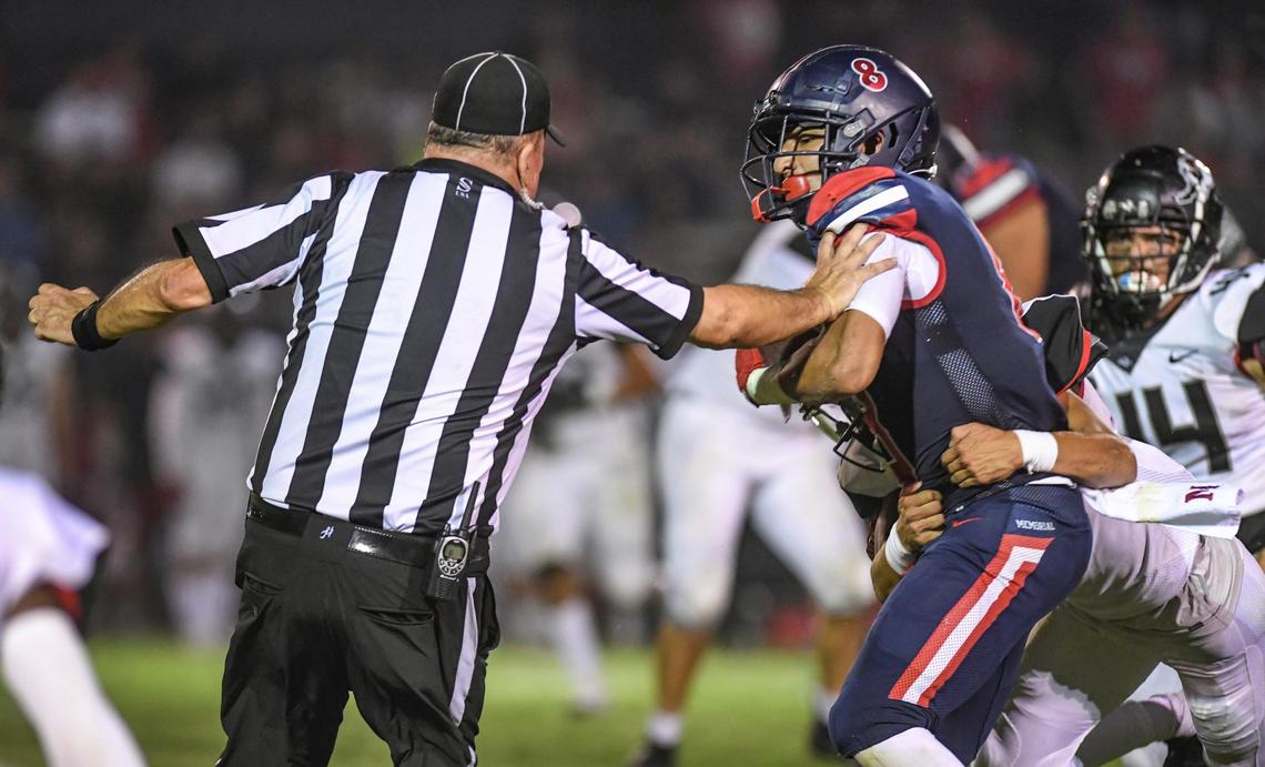 Memorial’s Brandon Ramirez, center, collides with a referee while being tackled after a run against Hanford in the first half of their game at San Joaquin Memorial on Friday, Aug. 27, 2021.