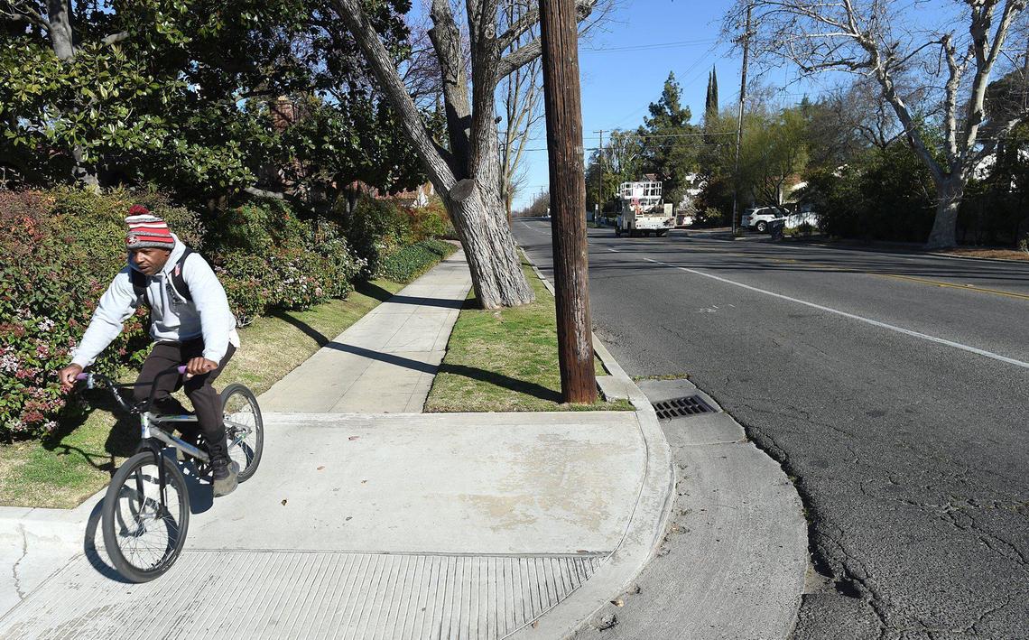 A cyclist takes the safer path, choosing the sidewalk, on Palm Avenue north of Clinton Avenue, on Feb. 16, 2022. A bike path will be installed this summer on Palm, reducing motor traffic to one-lane in each direction.