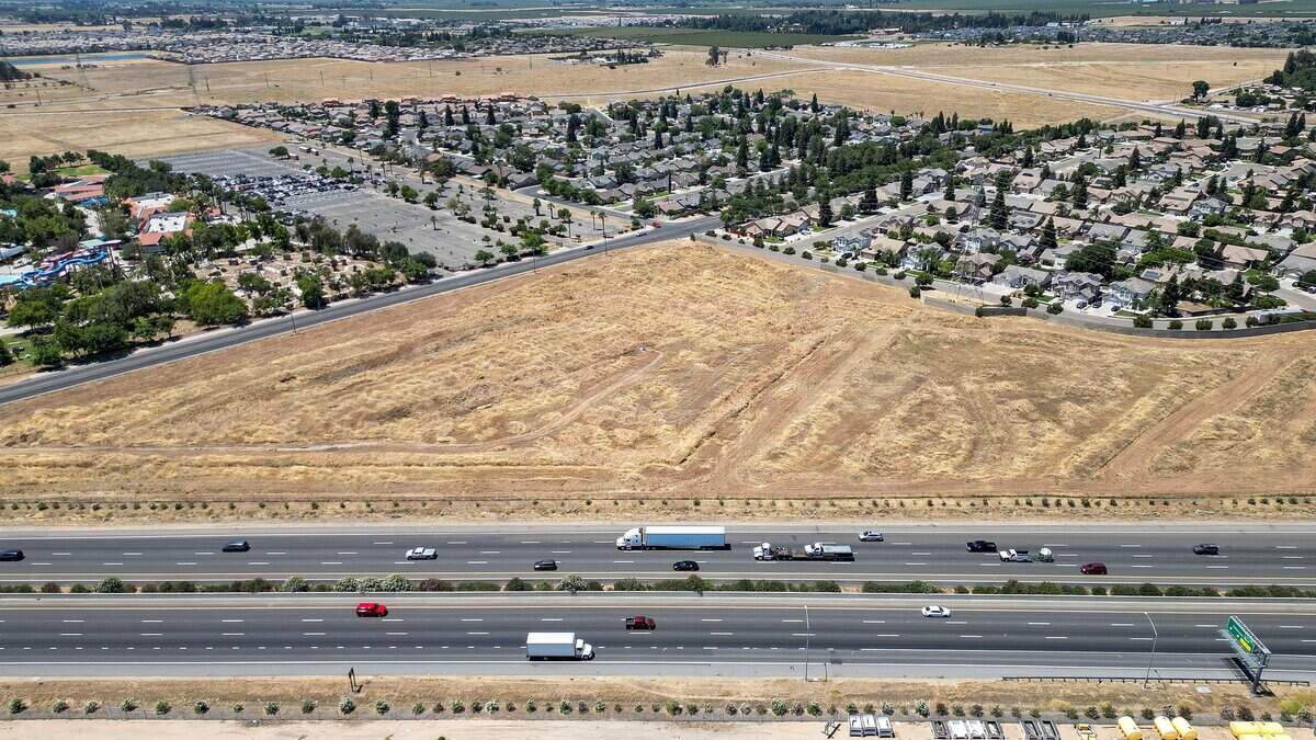 An empty lot situated between a home development, top and right, Highway 99, bottom, and Island Waterpark, left, in west Fresno is being proposed for development into a truck parking with about 150 stalls, truck wash and repair shop plus storage units.
