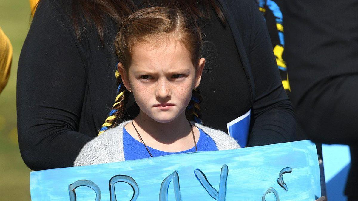 9-year-old Daniella Groth, whose family is from Ukraine, stands with others in support of the country, at a flag-raising ceremony, with the Ukrainian and American flags raised at Unity Park at Eaton Plaza, March 1, 2022, as a show of solidarity for the Ukrainian people.