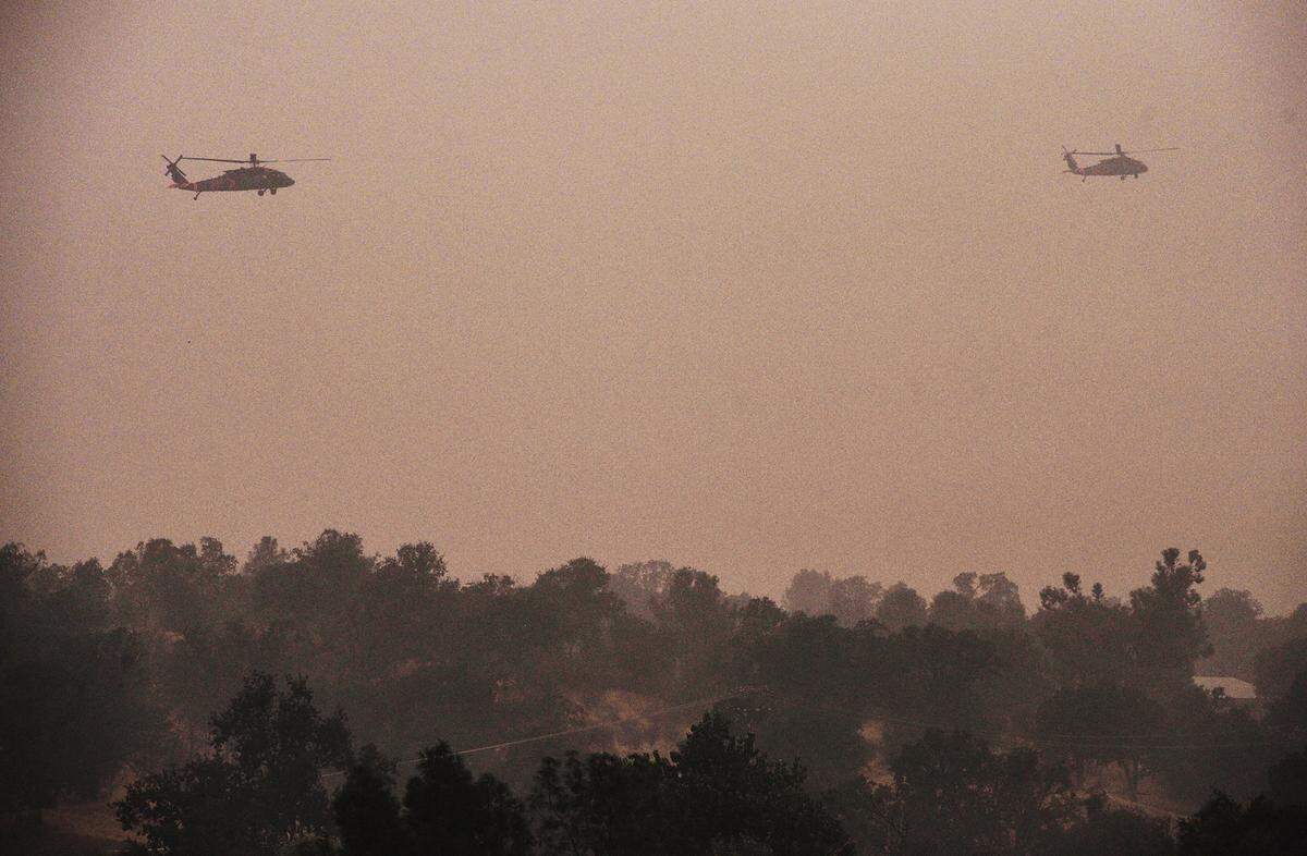 Air National Guard Blackhawk helicopters fly over a ridge at the Creek Fire north of Auberry Friday morning, Sept. 11, 2020.
