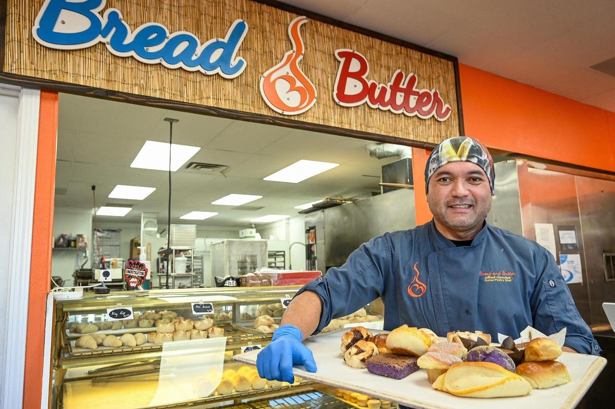 Mark Sanchez holds up various types of breads and desserts he now makes at Bread and Butter Filipino bakery which recently opened near Fresno and Gettysburg.
