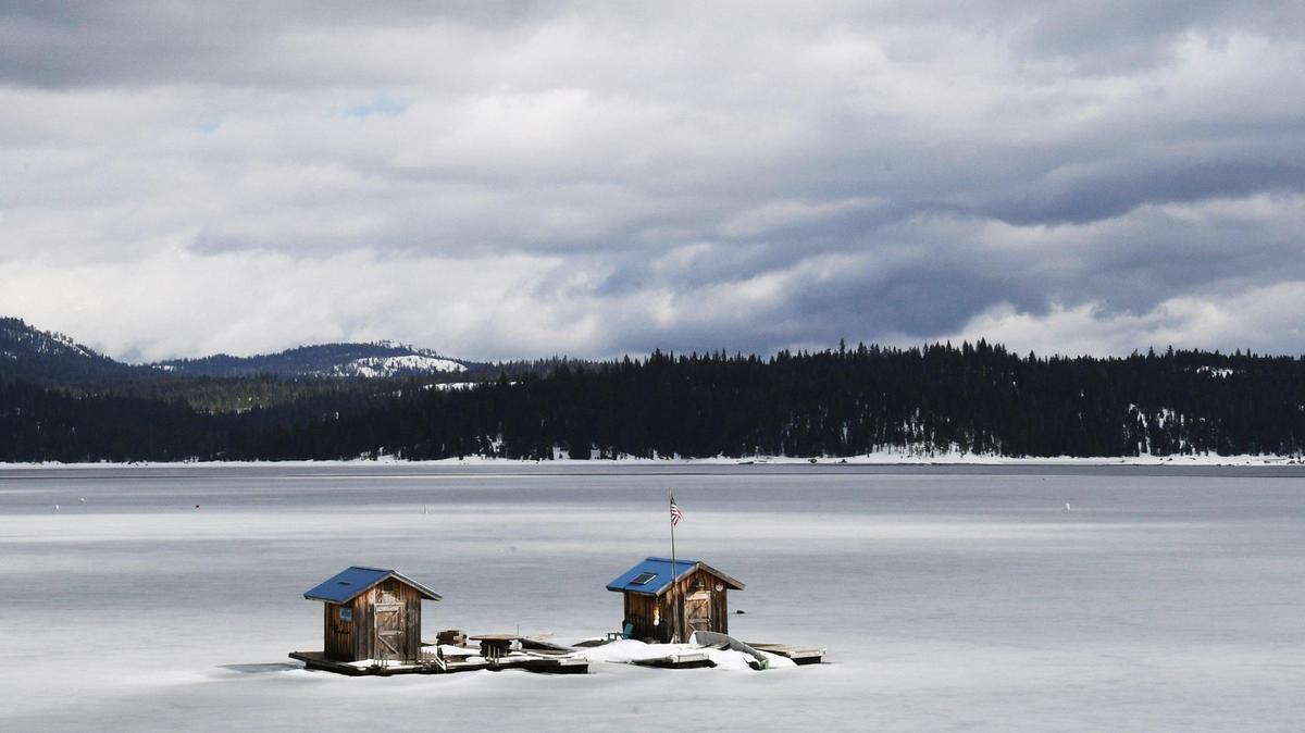 The sun briefly breaks through clouds highlighting structures for Shaver Lake Watersports surrounded by ice between storms Friday afternoon, March 17, 2023 at Shaver Lake.