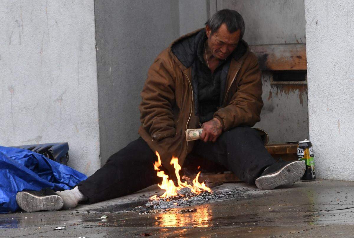 A homeless man tries keeping warm in a Chinatown doorway during the storm Tuesday, Dec. 14, 2021.