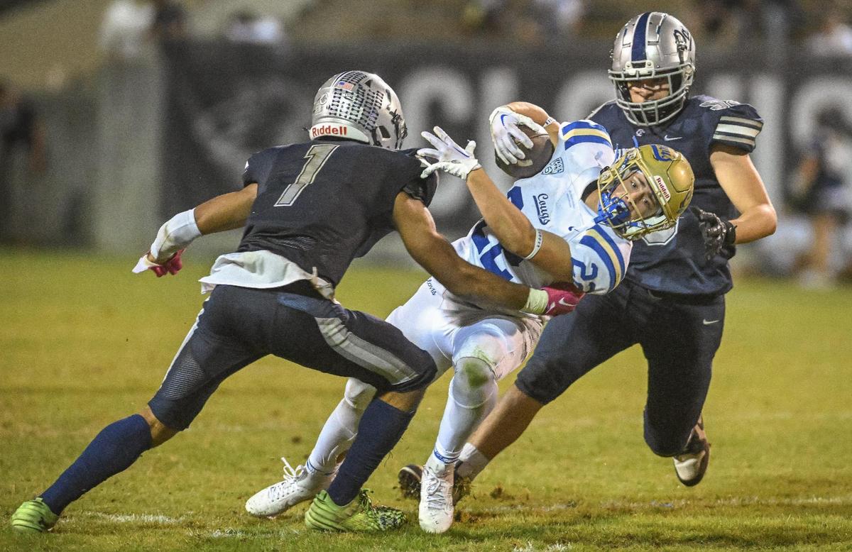 Clovis’ Maddox Merrill, center, tries to squeeze past Clovis East defenders Tommy Nix, left, and Caleb Solis but is stopped for a loss during their game at Lamonica Stadium on Friday, Oct. 20, 2023.