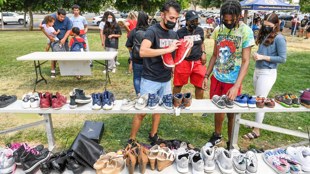 Volunteers check shoe sizes while giving out shoes to families at Cary Park in Fresno during the Community Kick it Outreach shoe giveaway on Saturday, Aug. 7, 2021.