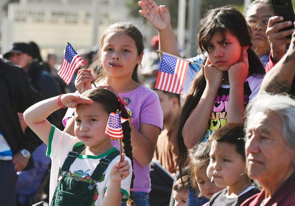 Children wave flags as the annual Central Valley Veterans Day Parade passes by Saturday, Nov. 11, 2023 in downtown Fresno.