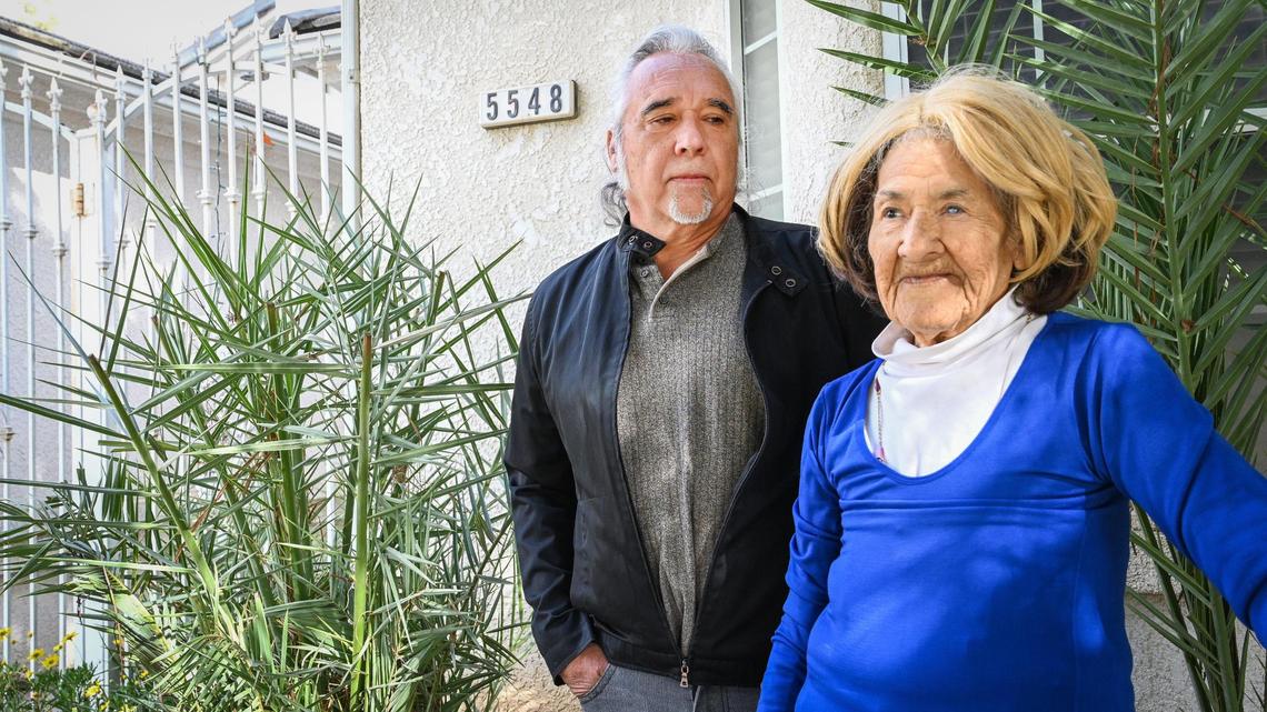 Maria Mogan and son Mike Mogan stand near the address number plate that had been covered by a palm frond, which has since been pruned, outside her northwest Fresno home Monday, Feb. 21, 2022.