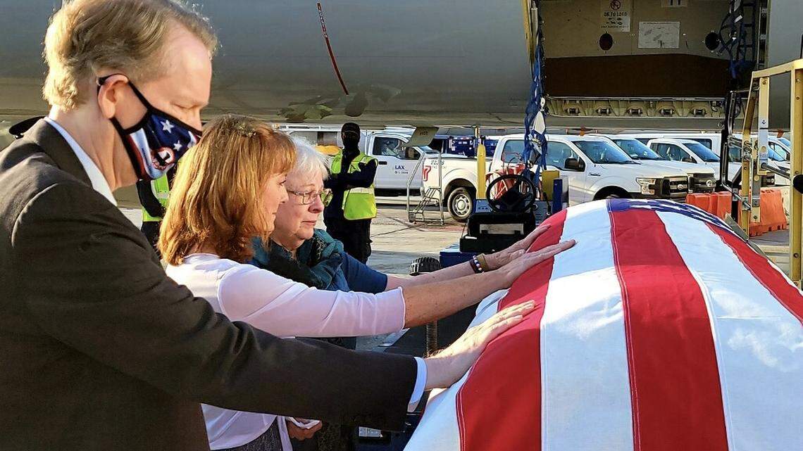 The remains of Marine Pfc. Royal Waltz, killed during World War II, are received by members of his family on Sept. 23, 2021 at the Los Angeles International Airport. Waltz’s family, from left: Cousin Jim Lovelace, great-niece Cindy Garcia, and niece Patricia Hanse Verheul, place their hands on the coffin carrying his remains before its driven north to Hanford, California.