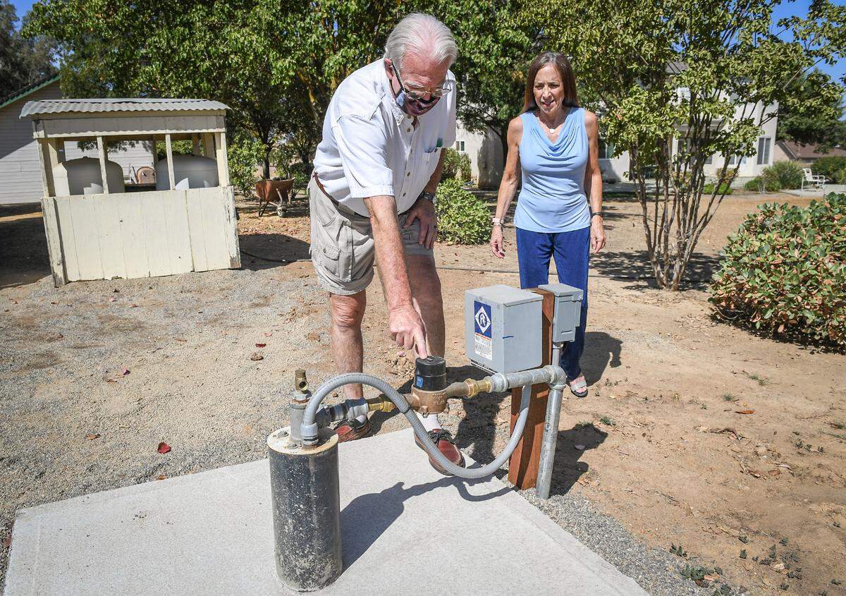 Michael and Rochelle Noblett look over the new water well they recently had installed for nearly $27,900 when their previous well ran dry, on Friday, Sept. 25, 2020. In the 1990s the Nobletts built a home on grazing land in Madera County to raise their kids and retire. At the height of the drought, a large farming operation began growing thousands of trees with deep wells.