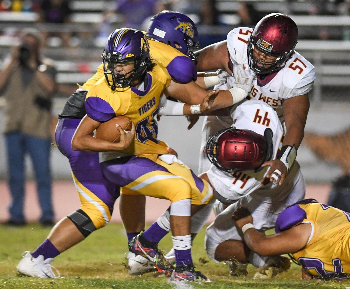 Lemoore quarterback Ty Chambers, left, tries to scramble away from the Clovis West defense on a keeper in the second half of their game at Lemoore High on Friday, Sept. 2, 2022.
