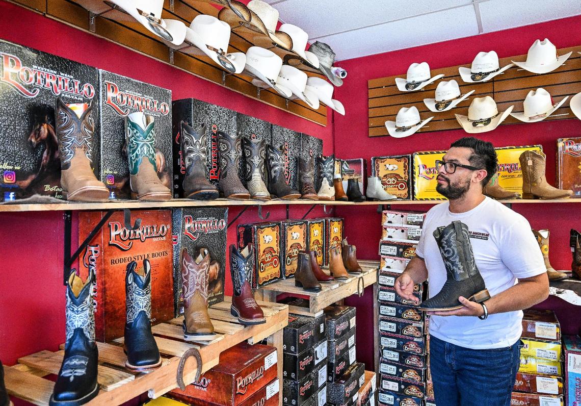 Owner Roman Rubio shows off some of the specialized cowboy boots on the shelves at Rubio Ranchwear in its new shop on Fulton near Highway 180 just north of downtown Fresno.
