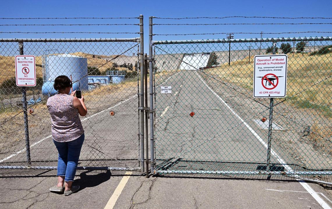 Madera’s Tasha Manfredi-Garlick takes a photo of Friant Dam releasing water from Millerton Lake Saturday, July 15, 2023 near Friant.