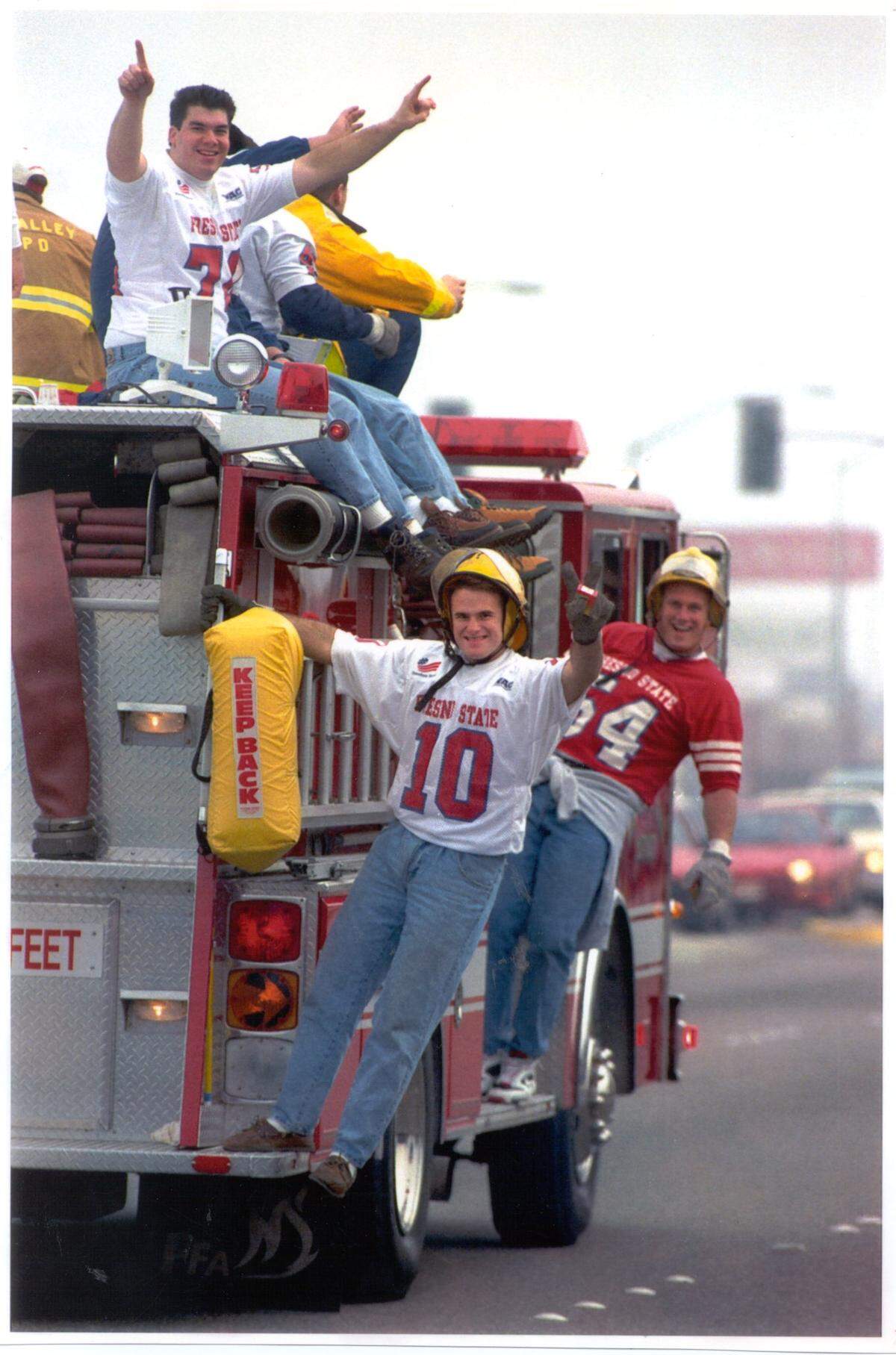On the parade down Shaw Avenue celebrating the Freedom Bowl victory, Bulldogs Derek Mahoney (10) and Brad Bell (54) hang off a firetruck.