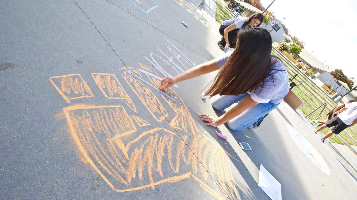 A student uses sidewalk chalk to spread a message to other students at Edison High School about voting.