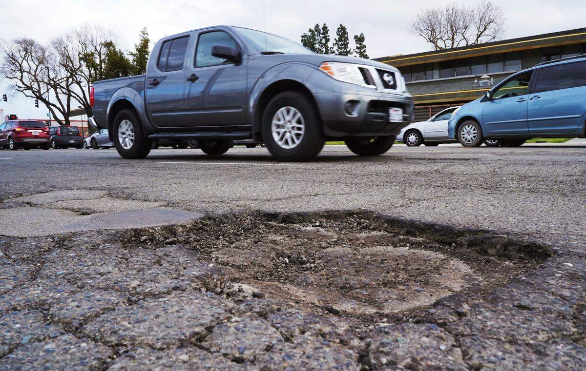 Traffic passes potholes along Ashlan Avenue just west of Blackstone Avenue Wednesday, March 29, 2023 in Fresno. Recent winter storms affected the road conditions.