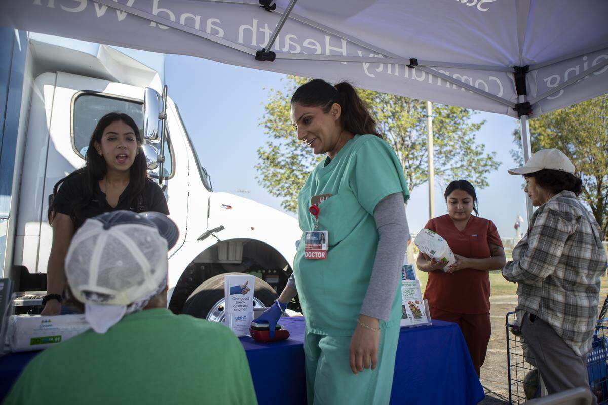 Dr. Navdeep Lehga examines a patient in the parking lot outside the Saint Agnes Mobile Health Unit clinic, located in Rojas Pierce Park in Mendota on Aug. 28, 2025. Photo by Larry Valenzuela, CalMatters/CatchLight Local
