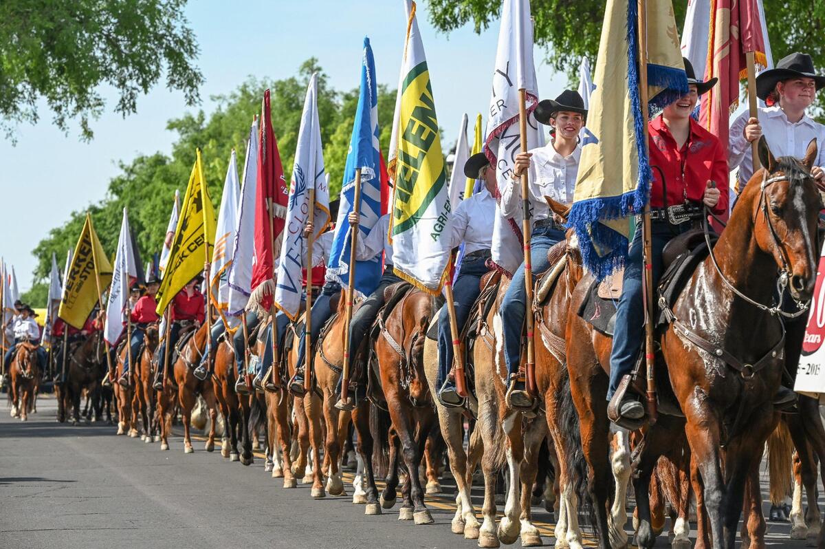 Parade participants mounted on horses hold sponsor flags as they head through Old Town Clovis during the 109th annual Clovis Rodeo Parade on Saturday, April 29, 2023.
