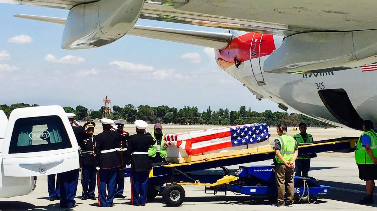The body of Mark Mitchell in a flag-draped casket is unloaded from a plane with the help of an honor guard at Fresno Yosemite International Airport on May 18, 2018.