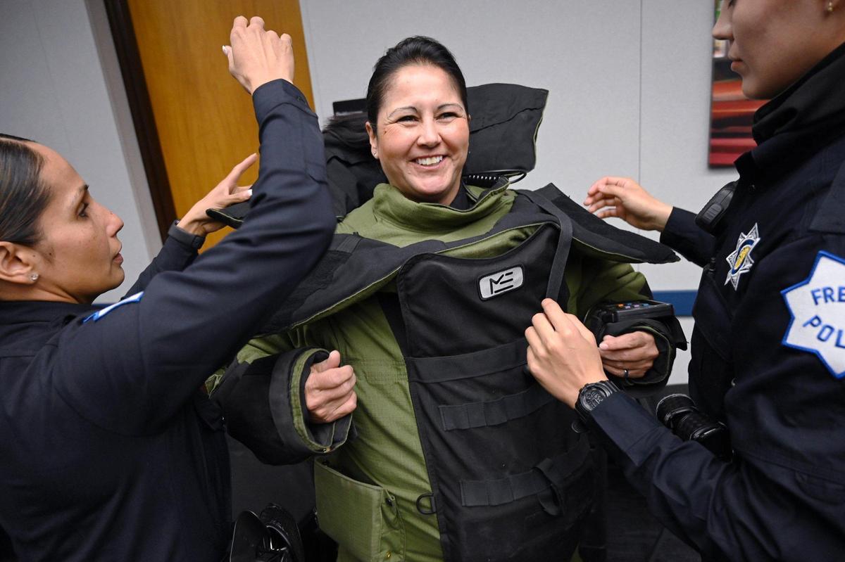Fresno Police detective and bomb technician Annette Arellanes is helped into her bomb suit before Fresno Chief of Police Paco Balderrama announced a commitment to the 30x30 Pledge, a focus on improving the representation of women in the police force at a news conference Friday, March 25, 2022 in Fresno. The national initiative’s focus is to increase the numbers to 30 percent of women in new police recruits by 2030.
