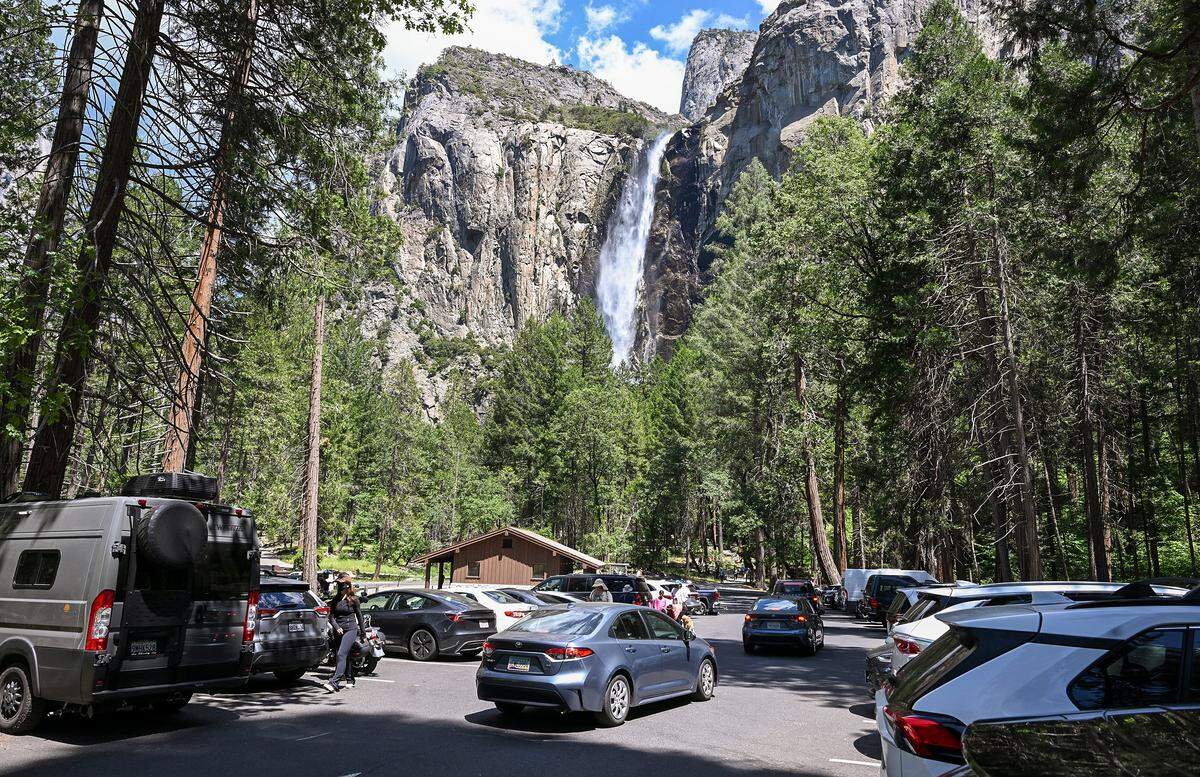 Water pours off of Bridalveil Fall as cars hunt for open parking stalls in the lot during a busy day at Yosemite National Park on Thursday, May 22, 2026.