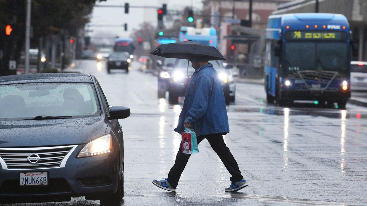 A man crosses Van Ness Ave as rain falls Tuesday morning, Dec. 27, 2022 in downtown Fresno.