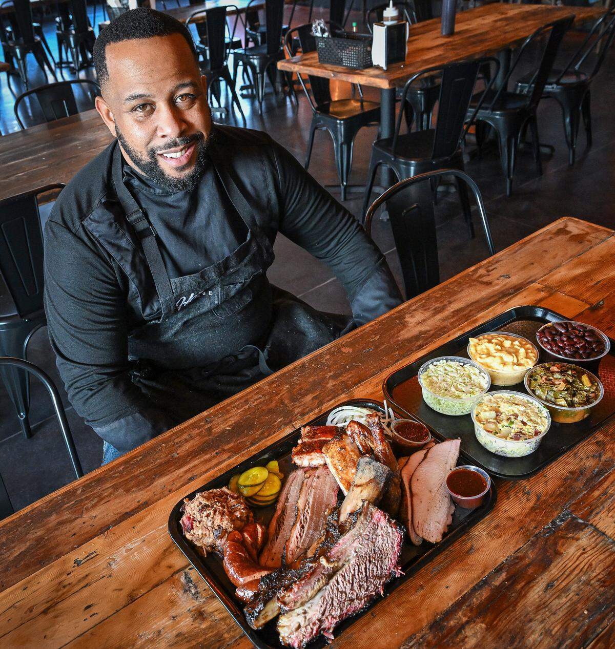 Fresno native and acclaimed barbecue chef Matt Horn sits with a selection of barbecue meats and sides at his new restaurant Horn Barbecue which opened in Fresno's Granite Park shopping center on Jan. 20, 2026.