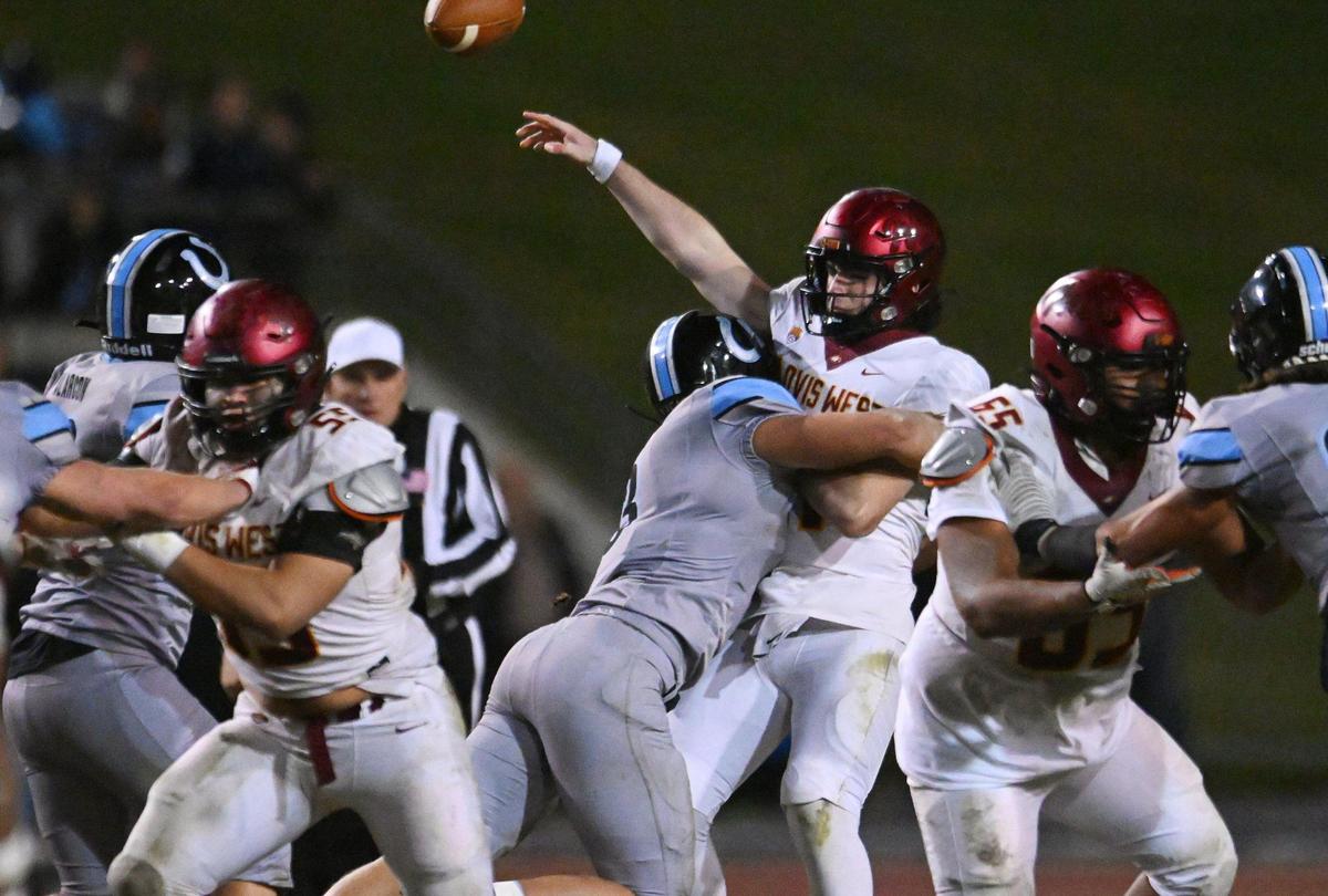 Clovis North’s McKay Madsen, center, pressures Clovis West’s quarterback Tyler Patrick in a Central Section Division I quarterfinal game Thursday, Nov. 9, 2023 in Clovis.