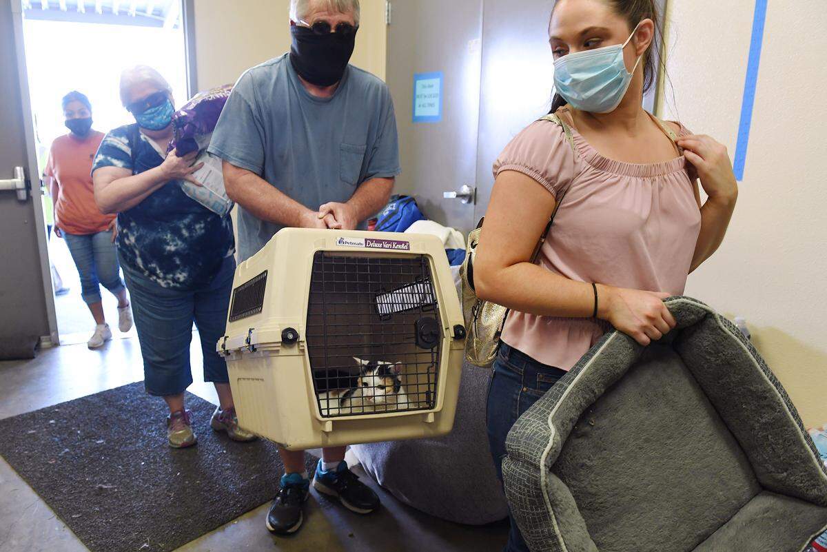 Tom Harris, center, stands in line carrying Kaze, peeking out of cage, after the family was evacuated from Tollhouse Tuesday afternoon, Sept. 8, 2020 in Clovis. Central California Animal Disaster Team, working with other groups, began safely storing pets at Granite Ridge Intermediate School for owners who had been evacuated from their homes due to the Creek Fire Tuesday afternoon, Sept. 8, 2020 in Clovis.