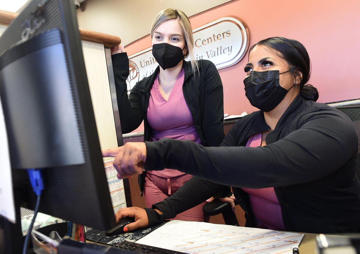 Medical assistants Grace Martinez, left, and Mary Rodriguez, go over data at Mendota’s United Health Center, April 28, 2021. Looming state changes, that would put health centers across the state, especially those in rural communities in the Central Valley, such as this one, at risk.