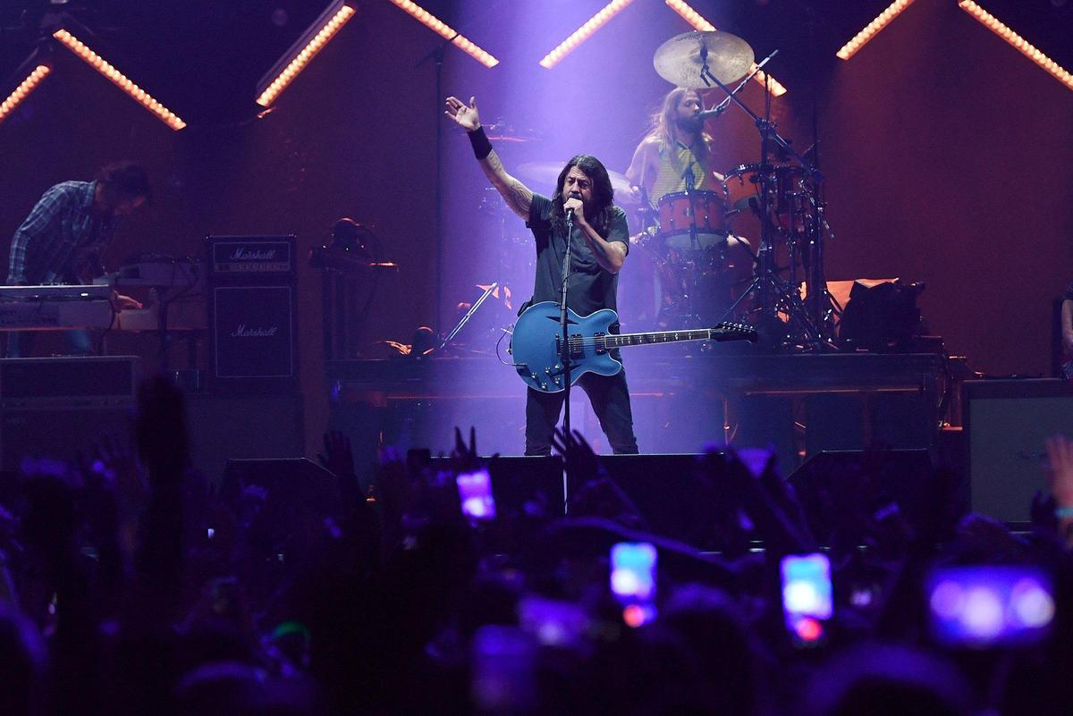 Foo Fighters lead singer Dave Grohl in a spotlight as they perform at Save Mart Center Thursday, Dec. 9, 2021 in Fresno. Drummer Taylor Hawkins performs behind him.