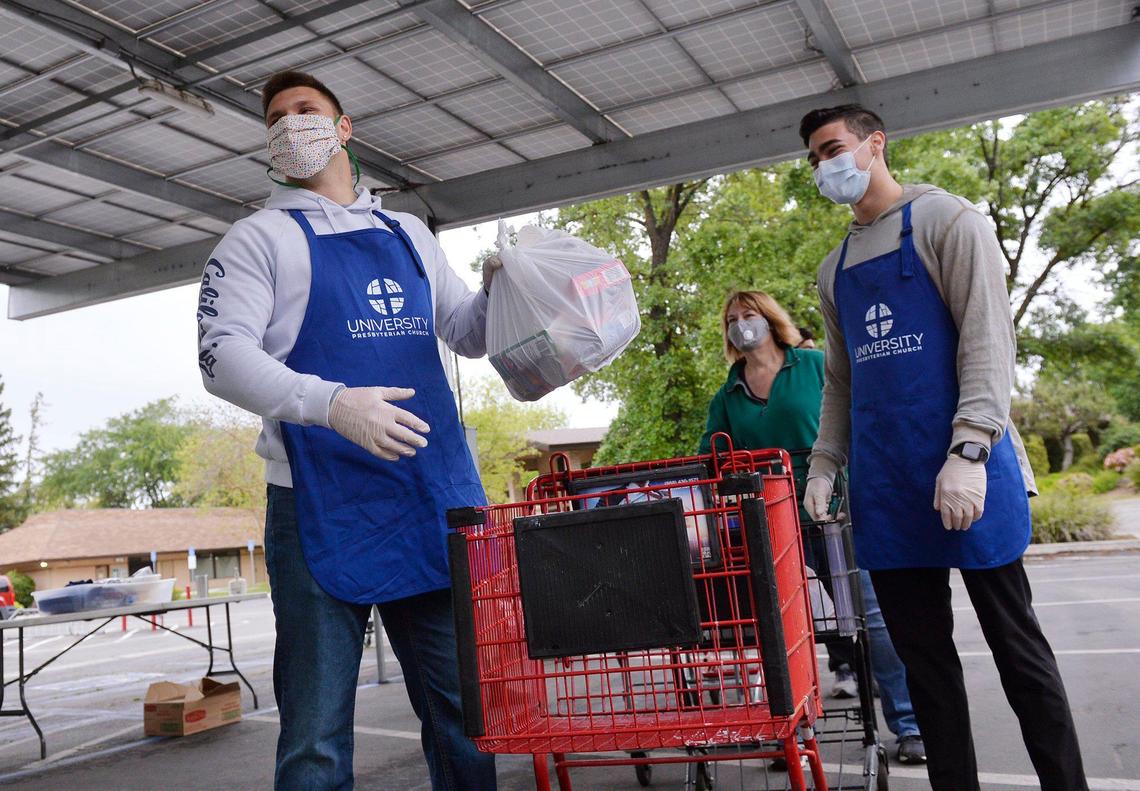 San Joaquin Memorial graduate and University of California, Berkeley’s Zach Angelillo, left, with childhood friend Austin Yniguez, right, helps distribute food at a giveaway held at University Presbyterian Church of Fresno Saturday morning, April 18, 2020 in Fresno.
